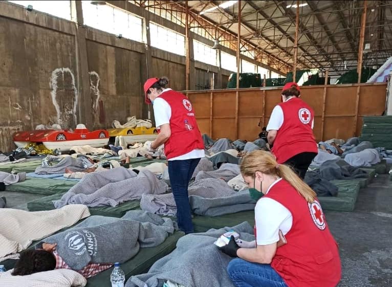 Φωτογραφία που δόθηκε σήμερα στη δημοσιότητα από τη συνδρομή του Ελληνικού Ερυθρού Σταυρού στα θύματα του τραγικού ναυαγίου στην Πύλο. Ο Ελληνικός Ερυθρός Σταυρός από τις πρώτες ώρες του τραγικού ναυαγίου στην Πύλο που κόστισε τη ζωή σε δεκάδες συνανθρώπους μας βρέθηκε στο πλευρό των άτυχων μεταναστών, συνδράμοντας με κάθε μέσο που διαθέτει τους διασωθέντες, οι οποίοι αντιμετωπίζουν σοβαρά σωματικά και ψυχολογικά προβλήματα υγείας. Συγκεκριμένα, στην Καλαμάτα επιχειρεί από την πρώτη στιγμή πολυμελές κλιμάκιο νοσηλευτικού προσωπικού και εθελοντών Τομέα Υγείας από το Περιφερειακό Τμήμα Καλαμάτας του Ε.Ε.Σ, καθώς και κλιμάκιο Εθελοντών Σαμαρειτών-Διασωστών που έσπευσε από την Πάτρα για να ενισχύσει τις δυνάμεις της Πολιτείας σε αυτή την εξαιρετικά δύσκολη συγκυρία. Τα κλιμάκια του Ε.Ε.Σ, τα οποία διανυκτέρευσαν στο πλευρό των μεταναστών, παρέχουν Πρώτες Βοήθειες στους Σταθμούς Πρώτων Βοηθειών του Ε.Ε.Σ. στο σημείο, διανέμουν είδη πρώτης ανάγκης και τρόφιμα, ενώ προσφέρουν ψυχολογική υποστήριξη στους διασωθέντες μετανάστες, οι οποίοι βρίσκονται σε άσχημη ψυχολογική κατάσταση. Τα κυριότερα προβλήματα υγείας που αντιμετωπίζουν είναι δευτερογενής πνιγμός, δύσπνοια, αφυδάτωση, κρίσεις άσθματος, υψηλός πυρετός, εξάντληση, δυσουρία, αιματουρία, ωτίτιδα κ.α. Παράλληλα, οι εθελοντές του Ε.Ε.Σ. ενισχύουν τις δυνάμεις του ΕΚΑΒ για μεταφορά των πιο σοβαρών περιστατικών στα νοσοκομεία της περιοχής. Τα κλιμάκια του Ε.Ε.Σ, βρισκόμενα σε συνεχή επικοινωνία και συνεργασία με τις Αρχές, θα παραμείνουν στο σημείο για όσο διάστημα χρειαστεί. Πέμπτη 15 Ιουνίου 2023. ΑΠΕ-ΜΠΕ/ΕΛΛΗΝΙΚΟΣ ΕΡΥΘΡΟΣ ΣΤΑΥΡΟΣ/STR