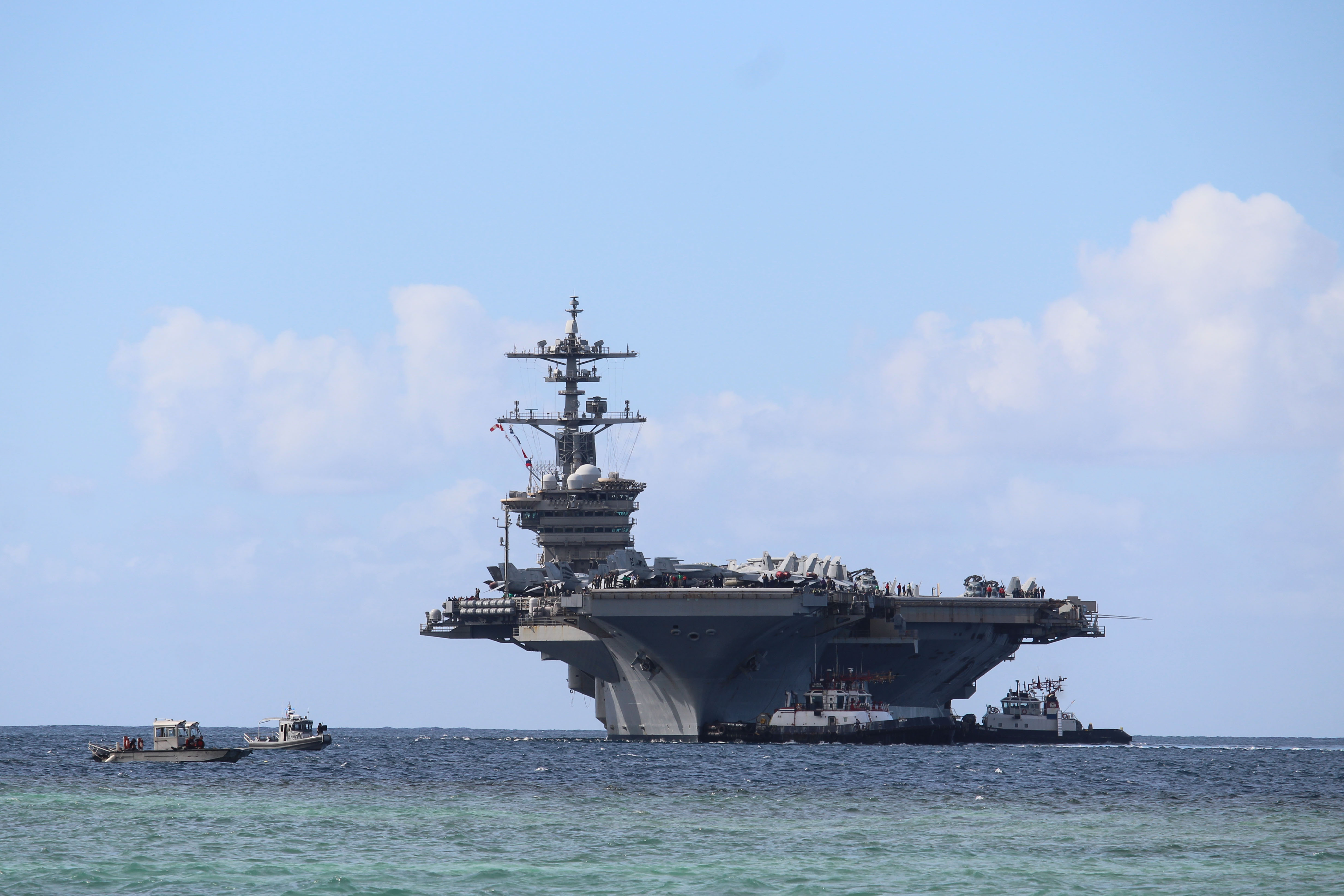 APRA HARBOR, Guam (Dec. 11, 2025) - Harbor tug boats guide Nimitz-class aircraft carrier USS Abraham Lincoln (CVN 72) as the ship pulls into Naval Base Guam for a scheduled port visit, Dec. 11. Abraham Lincoln Strike Group is on a scheduled deployment in the U.S. 7th Fleet area of operations to enhance interoperability through alliances and partnerships while serving as a ready-response force in support of a free and open Indo-Pacific region. (U.S. Navy photo by Valerie Maigue)